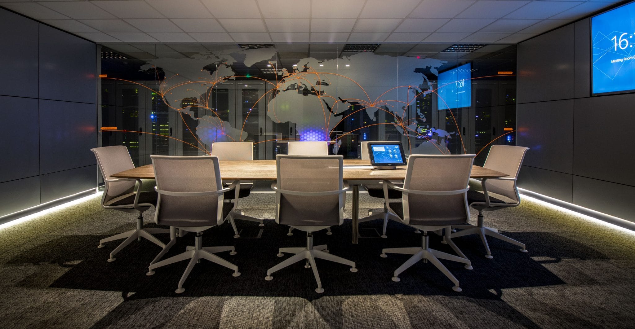 Boardroom with a glass world-map graphic looking into the data centre