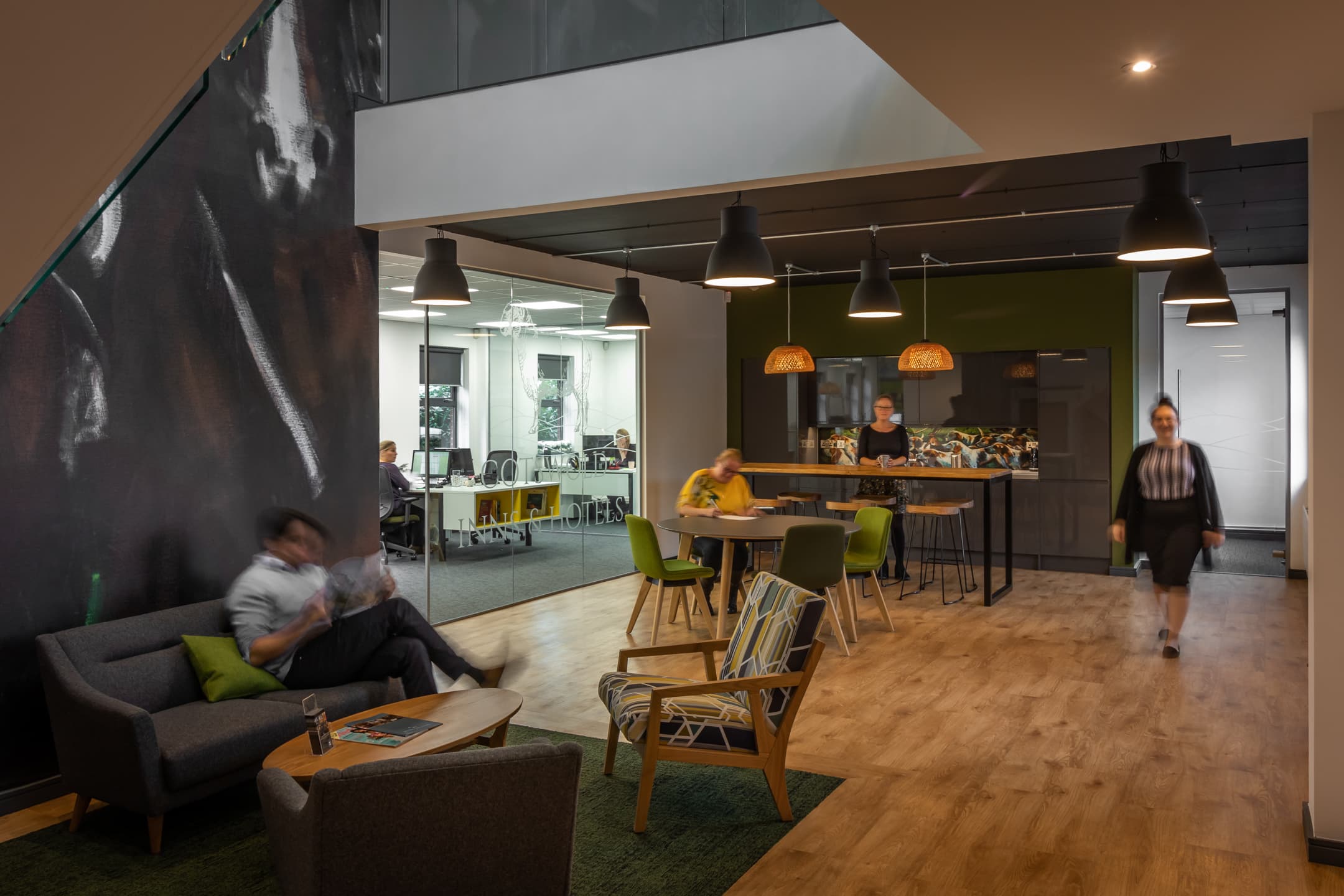 Double-height atrium with orange pendant lights and informal meeting areas